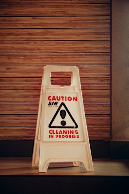 A team of three professional cleaners from Cleaners Edgware performing surface cleaning and deep cleaning in a modern living room. The room features a large fabric sofa with a wooden coffee table, two
